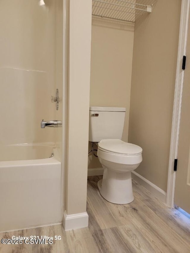 bathroom with toilet, shower / bath combination, baseboards, and wood finished floors