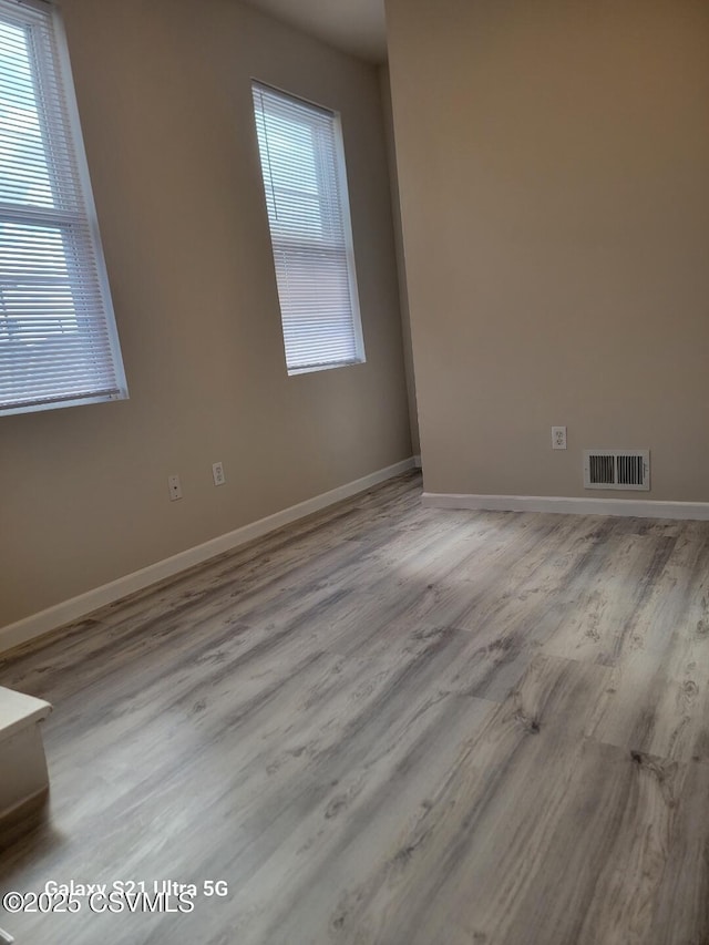 unfurnished room featuring visible vents, baseboards, and wood finished floors