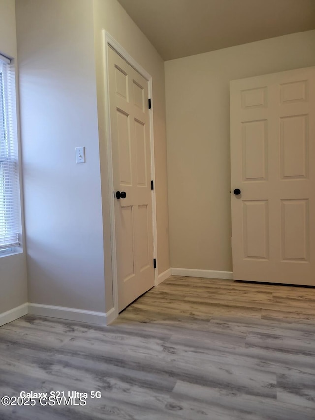 empty room with wood finished floors, a healthy amount of sunlight, and baseboards