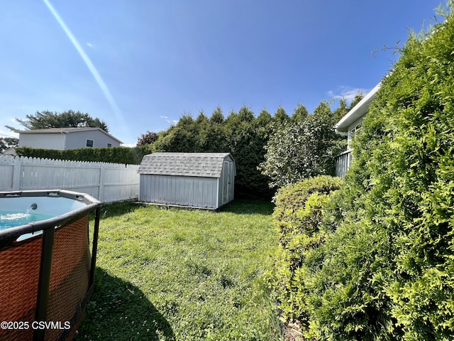 view of yard featuring a shed, fence, and an outbuilding