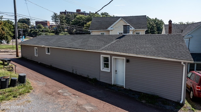 back of house with roof with shingles