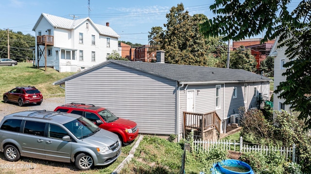 view of home's exterior with roof with shingles and fence