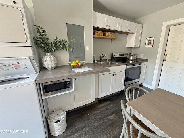 kitchen with stacked washer / drying machine, appliances with stainless steel finishes, white cabinets, a sink, and electric panel