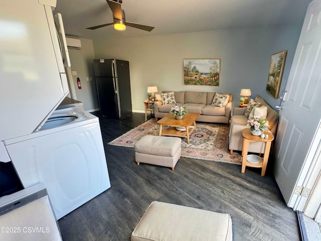 living room with a wall unit AC, stacked washer and dryer, ceiling fan, and dark wood finished floors