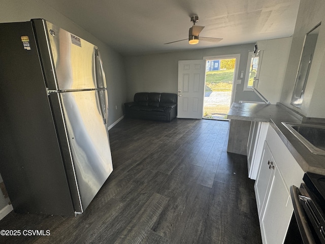 kitchen with white cabinets, a ceiling fan, dark wood-type flooring, stainless steel appliances, and a sink