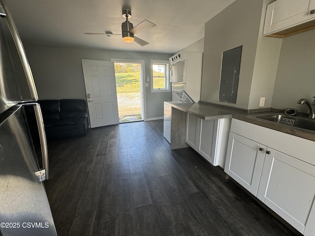 kitchen featuring electric panel, white cabinets, dark wood-style floors, freestanding refrigerator, and a sink