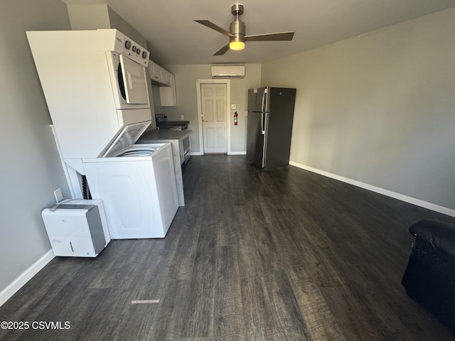 clothes washing area featuring laundry area, baseboards, dark wood-style flooring, stacked washer / drying machine, and a wall mounted AC