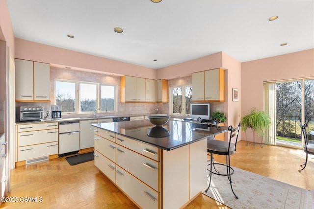 kitchen featuring tasteful backsplash, plenty of natural light, a kitchen breakfast bar, and a sink