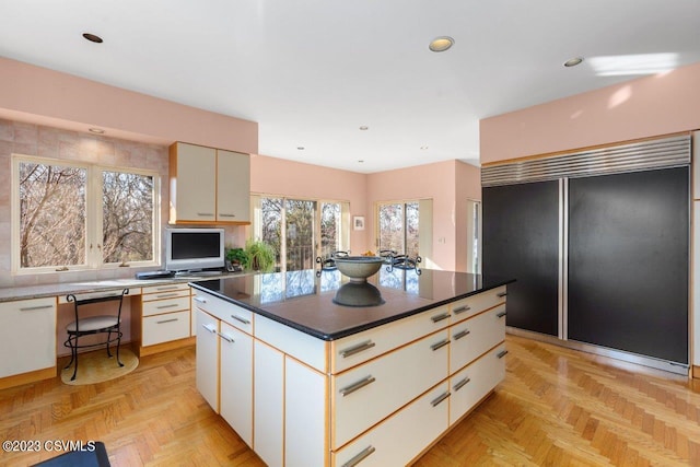 kitchen with built in refrigerator, a kitchen island, white cabinets, and recessed lighting