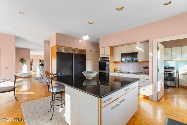 kitchen with decorative backsplash, a kitchen island, a kitchen breakfast bar, black appliances, and recessed lighting