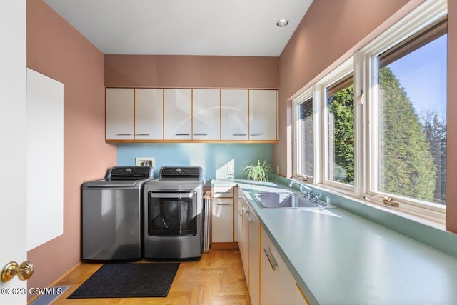 laundry room featuring washing machine and dryer, cabinet space, a sink, and recessed lighting