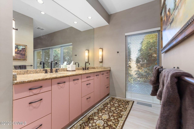 full bathroom with recessed lighting, visible vents, a sink, and wood finished floors