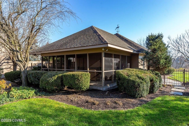 rear view of property with a shingled roof, a lawn, fence, and a sunroom