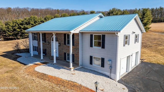 view of front of property featuring a garage, metal roof, driveway, and a porch