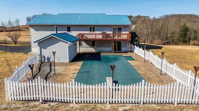 back of property featuring metal roof, a fenced backyard, a patio, and a deck