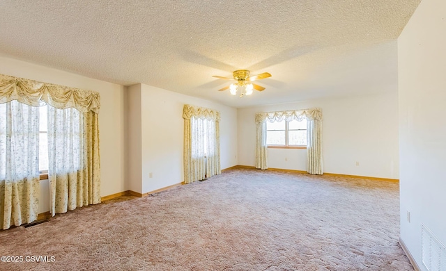 spare room with baseboards, visible vents, ceiling fan, a textured ceiling, and carpet flooring