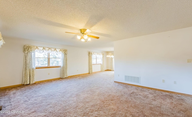 empty room featuring visible vents, carpet floors, baseboards, and ceiling fan with notable chandelier