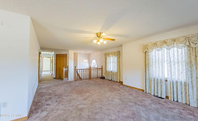 empty room featuring baseboards, carpet flooring, a textured ceiling, and a ceiling fan