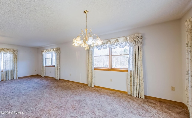 unfurnished room with a notable chandelier, baseboards, carpet floors, and a textured ceiling