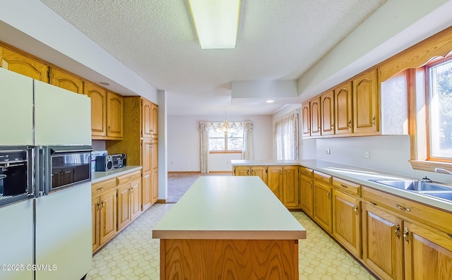 kitchen featuring light floors, a peninsula, a sink, light countertops, and white refrigerator with ice dispenser