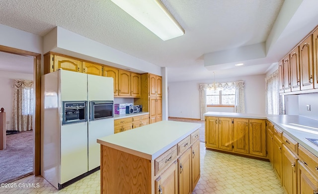 kitchen with light floors, a peninsula, white refrigerator with ice dispenser, and light countertops