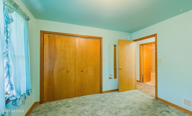 unfurnished bedroom featuring carpet, visible vents, a closet, and baseboards