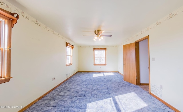 carpeted spare room with a ceiling fan and baseboards