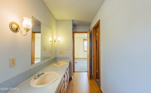 bathroom with double vanity, wood finished floors, and a sink