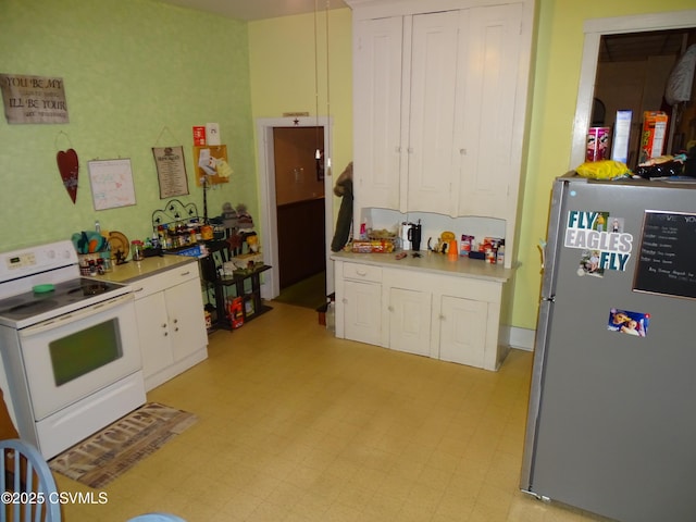 kitchen featuring white electric range oven, white cabinets, freestanding refrigerator, light countertops, and light floors