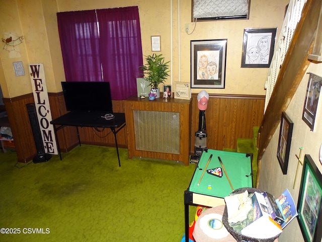 recreation room with carpet floors, wooden walls, and wainscoting