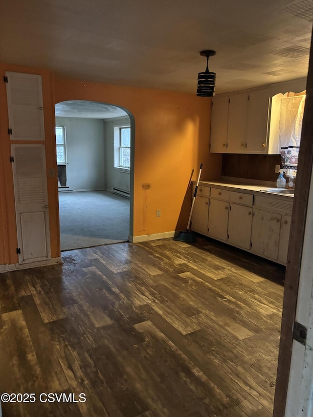 kitchen featuring a baseboard heating unit, white cabinetry, arched walkways, and dark wood-style flooring