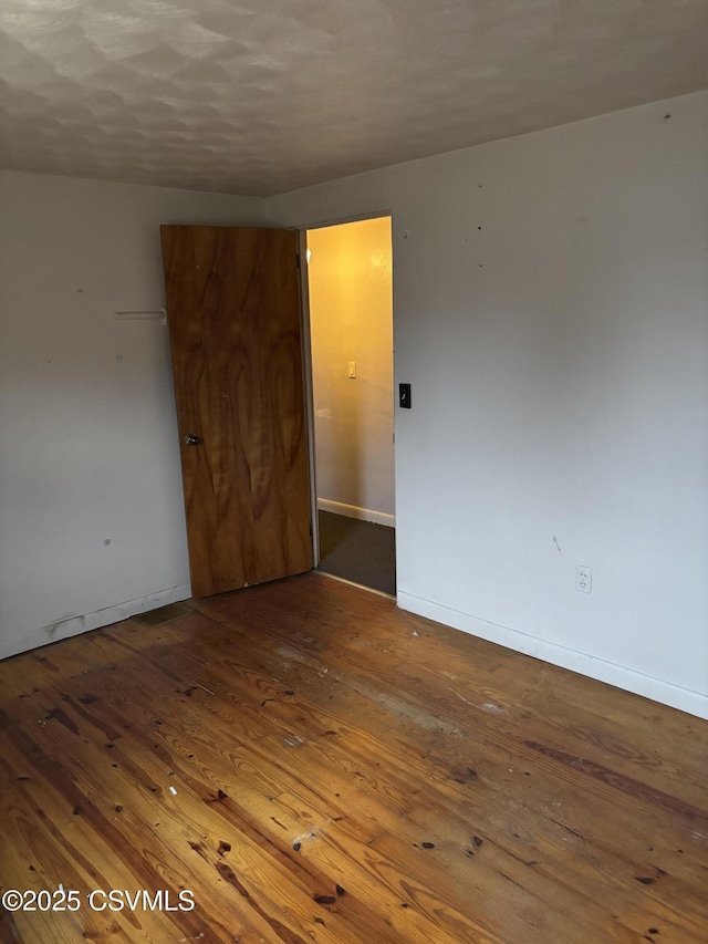 spare room with wood-type flooring and baseboards