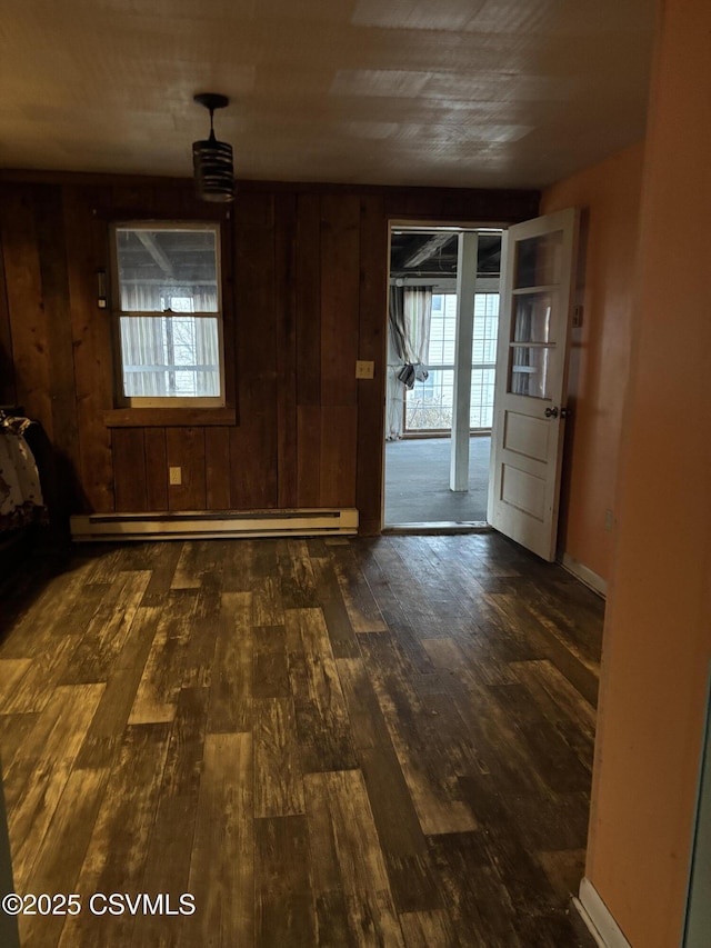 interior space with wood walls, plenty of natural light, a baseboard heating unit, and hardwood / wood-style floors