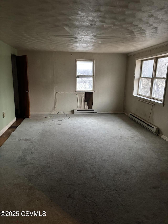 carpeted empty room with baseboard heating and baseboards