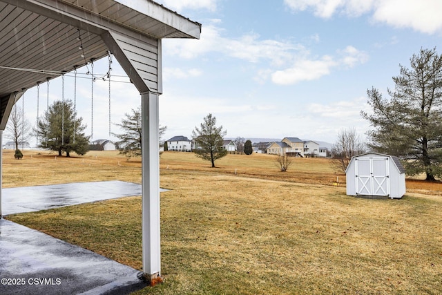 view of yard featuring a residential view, an outdoor structure, and a shed