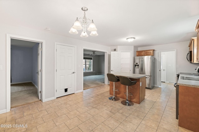 kitchen featuring a breakfast bar area, a center island, baseboards, appliances with stainless steel finishes, and brown cabinets