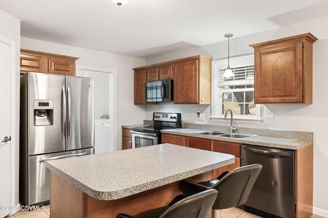 kitchen featuring a breakfast bar area, decorative light fixtures, a center island, stainless steel appliances, and a sink