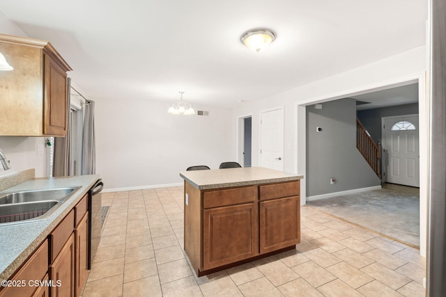 kitchen featuring brown cabinetry, a sink, baseboards, and a kitchen island