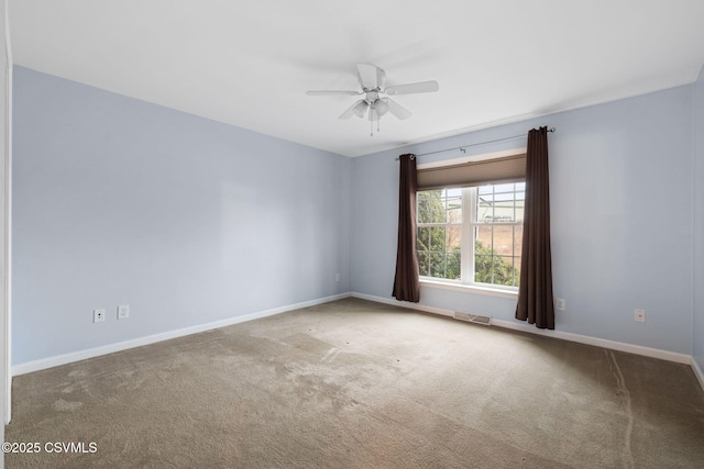 empty room with carpet floors, visible vents, baseboards, and a ceiling fan