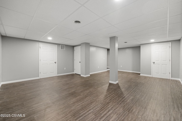 finished basement with dark wood-type flooring, visible vents, a drop ceiling, and baseboards