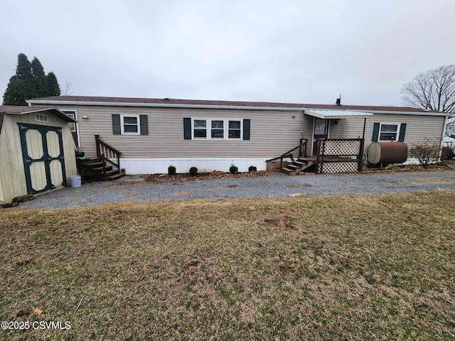 rear view of house featuring entry steps, an outdoor structure, heating fuel, and a shed