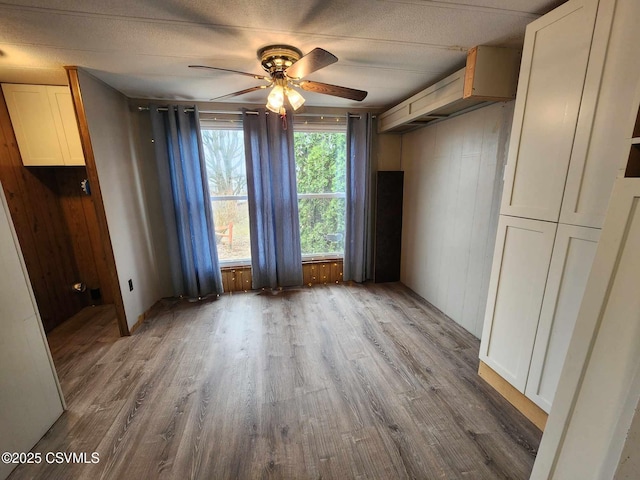 interior space with a textured ceiling, a ceiling fan, and wood finished floors