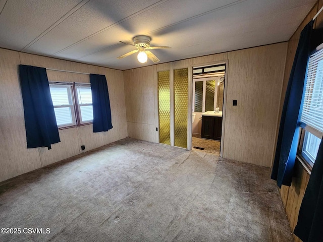 unfurnished bedroom featuring carpet floors, ceiling fan, and ensuite bathroom