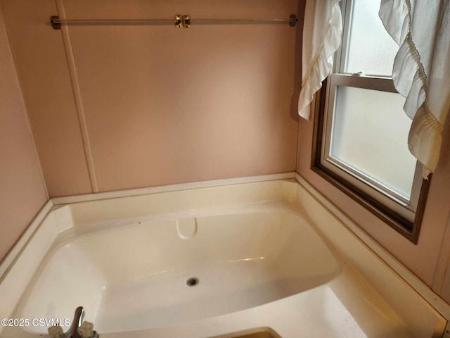 bathroom with a garden tub and a healthy amount of sunlight