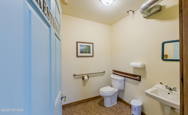 half bathroom with a sink, baseboards, toilet, and tile patterned flooring