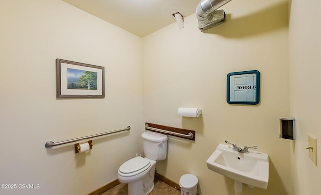 bathroom featuring tile patterned flooring, toilet, baseboards, and a sink