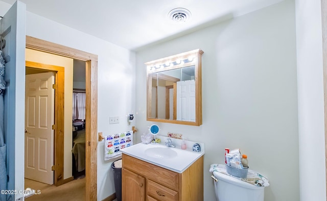 bathroom with vanity, toilet, and visible vents