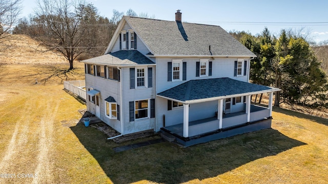 farmhouse-style home featuring a porch, a front lawn, a chimney, and roof with shingles