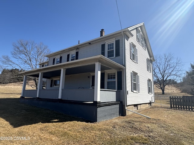 view of front of home with fence, covered porch, and a chimney