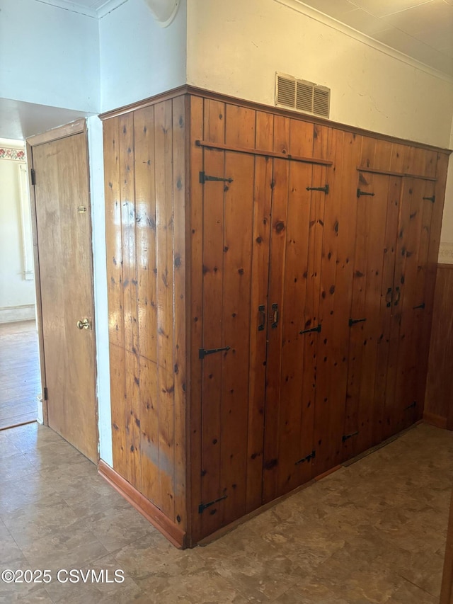 interior space with tile patterned floors, wooden walls, visible vents, and a wainscoted wall